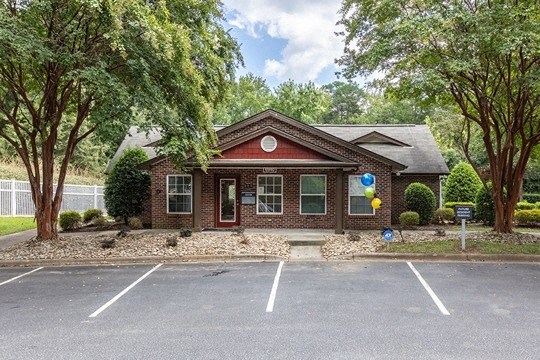a small brick house in a parking lot with trees