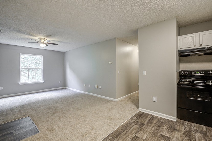 an empty living room and kitchen with a ceiling fan