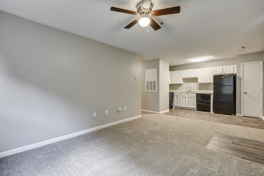 an empty living room and kitchen with a ceiling fan