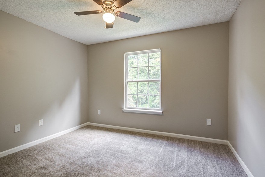 an empty room with a ceiling fan and a window