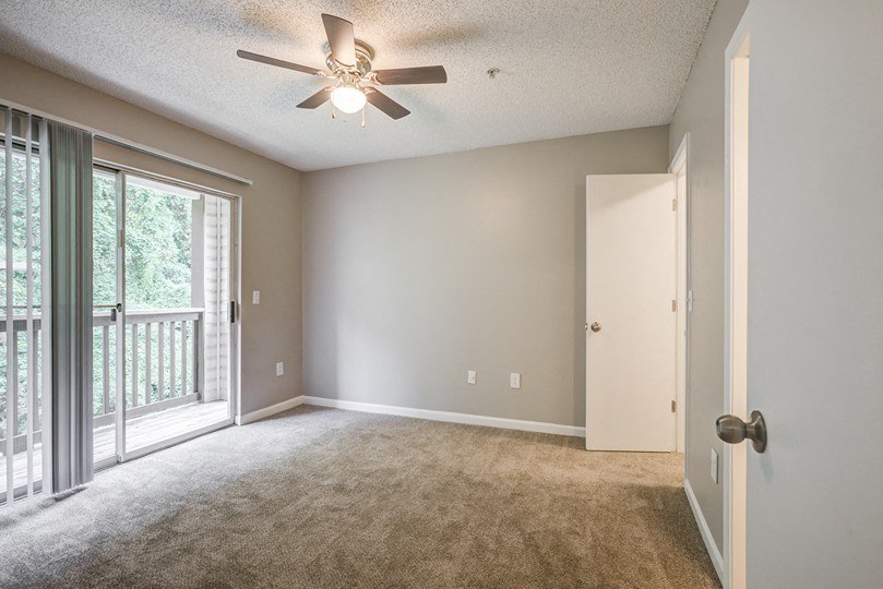 an empty living room with a ceiling fan and a window