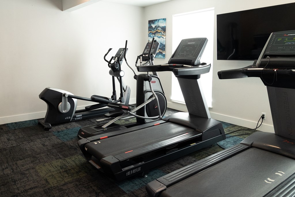 two treadmills and a treadmill in a room with a tv