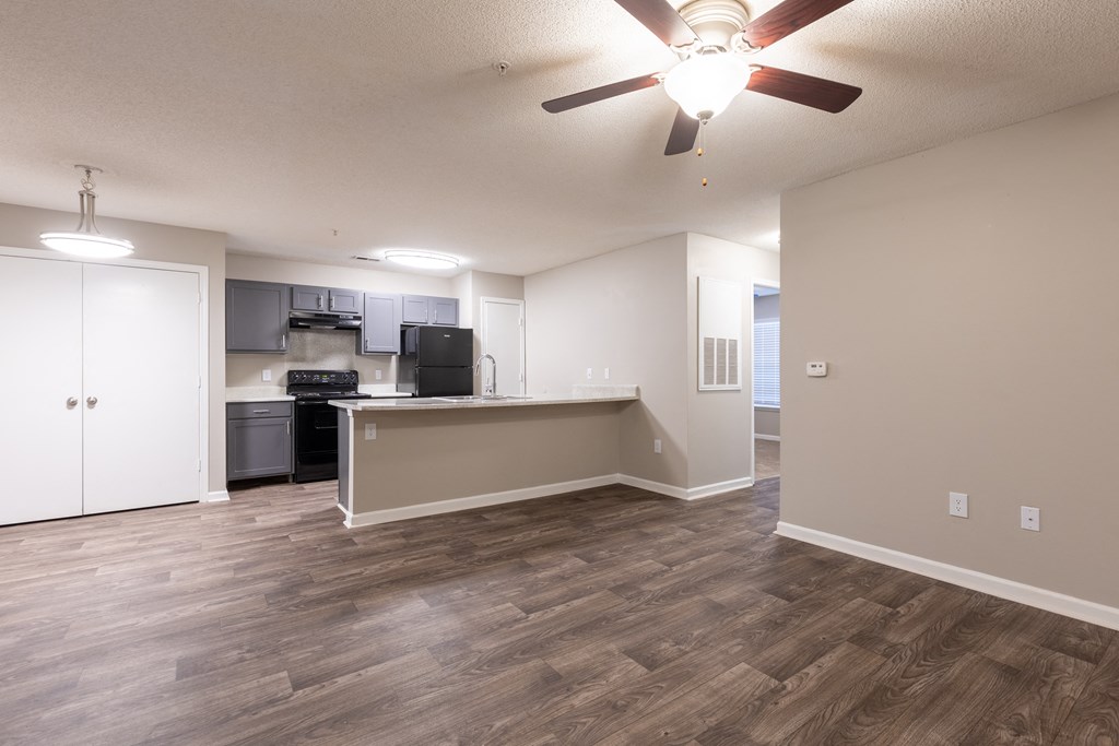 an empty living room and kitchen with a ceiling fan