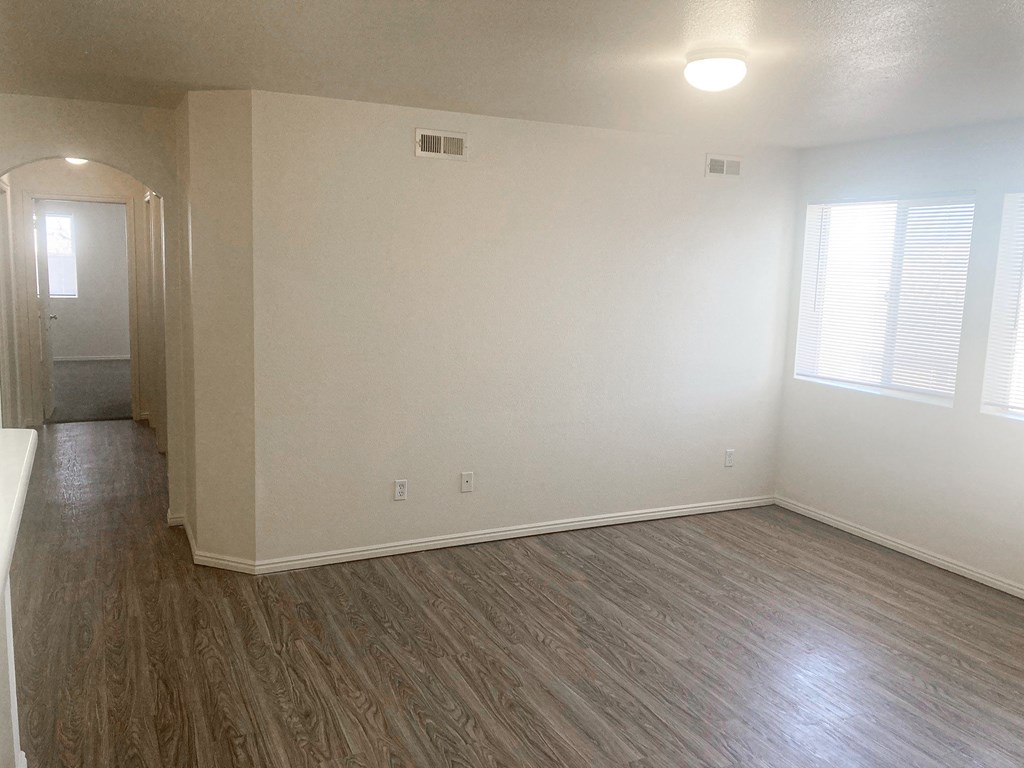 an empty living room with white walls and wood floors