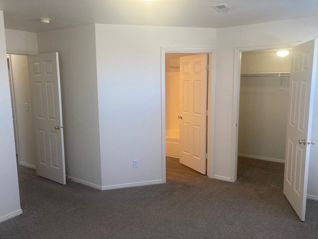 a bedroom with two doors and a closet and a door to a hallway