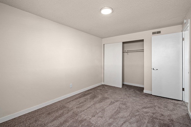 a bedroom with a carpeted floor and a door to a closet