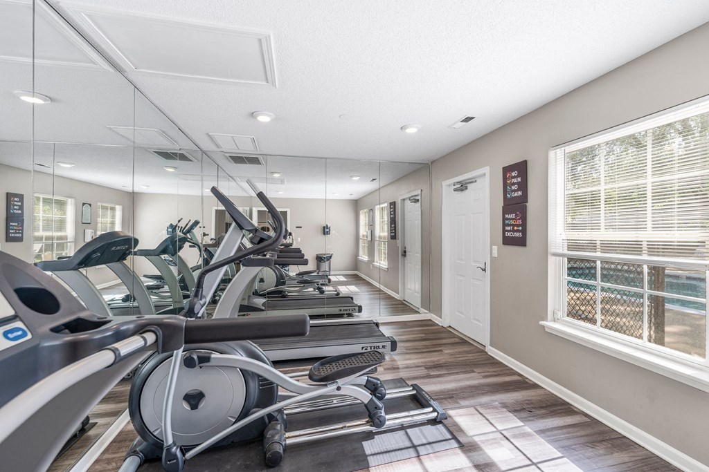 the gym is equipped with cardio equipment and a large window