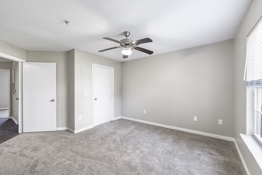 an empty living room with a ceiling fan