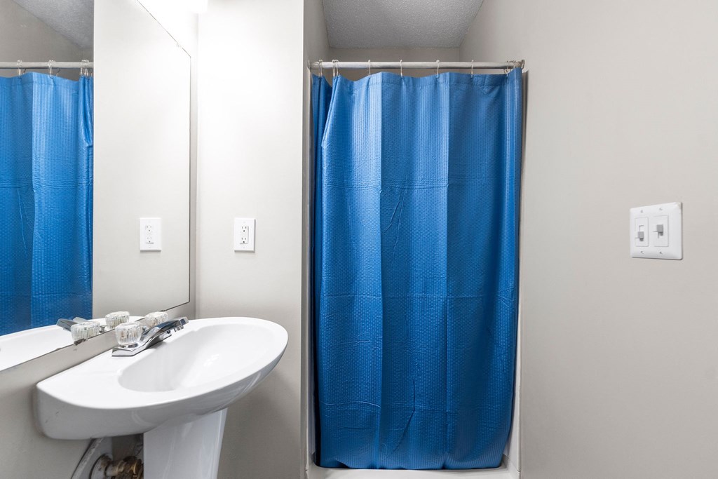 a bathroom with a blue shower curtain and a sink