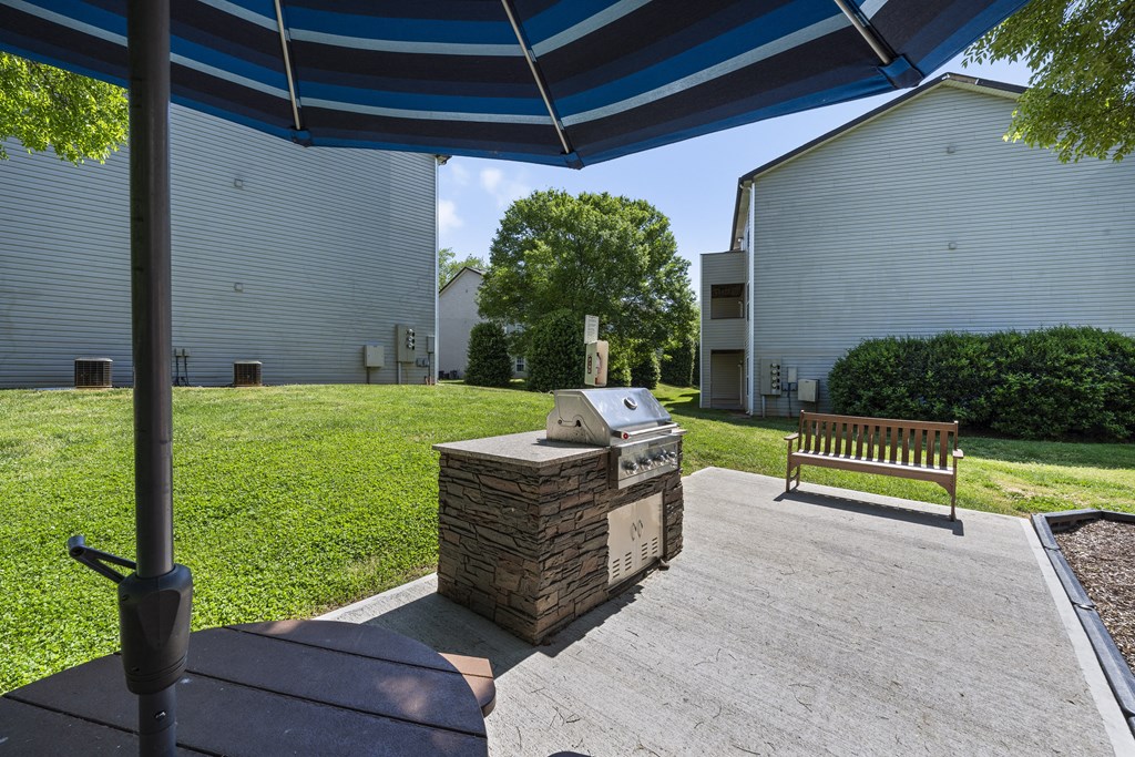 a patio with an outdoor grill and a table with an umbrella