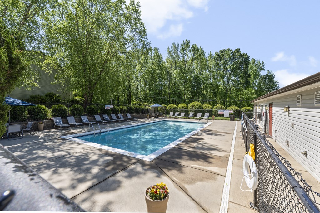 a swimming pool with chairs around it next to a building