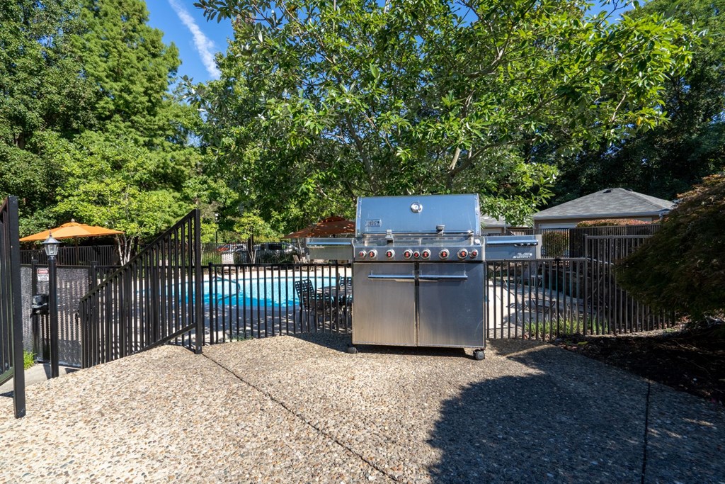 a stainless steel grill in a backyard with a swimming pool