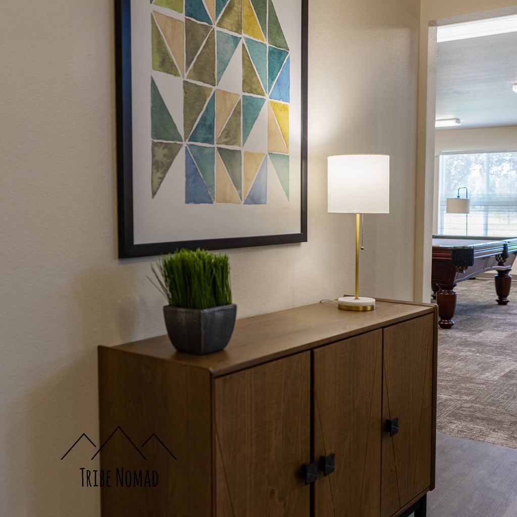 a living room with a cabinet and a lamp and a painting on the wall
