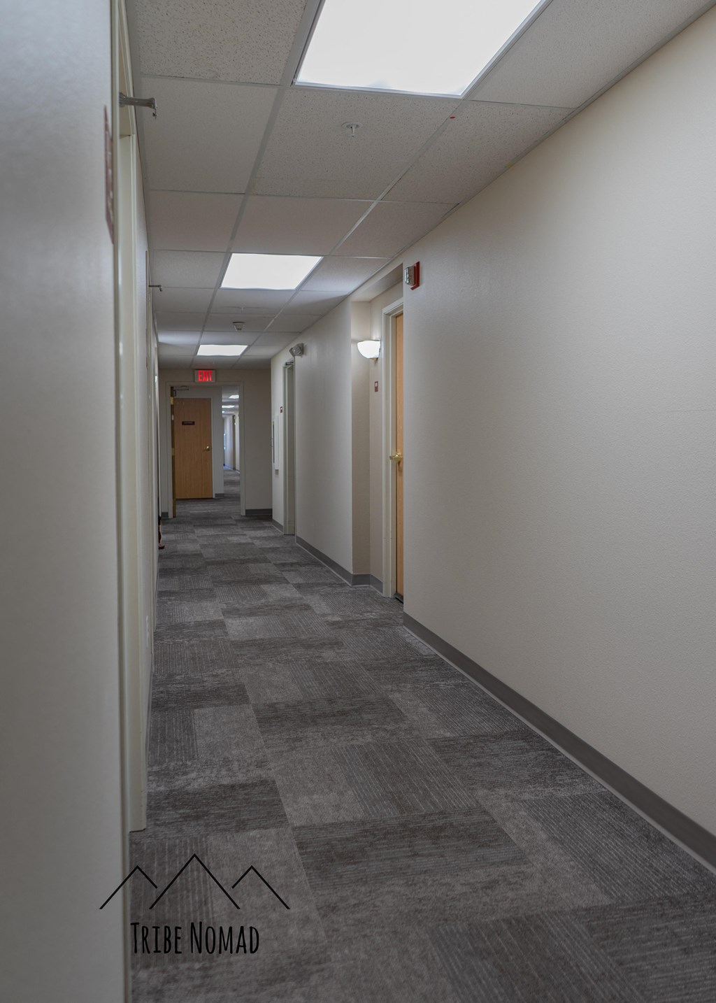 a long hallway with white walls and tile flooring and a light on the ceiling