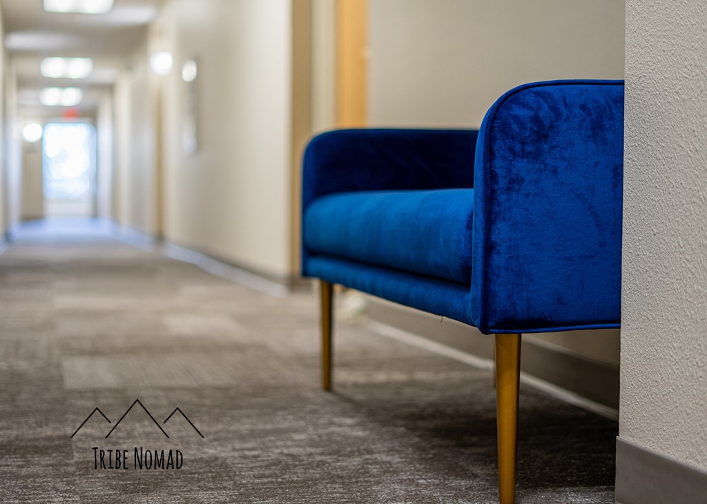 a blue chair in a room with a hallway in the background
