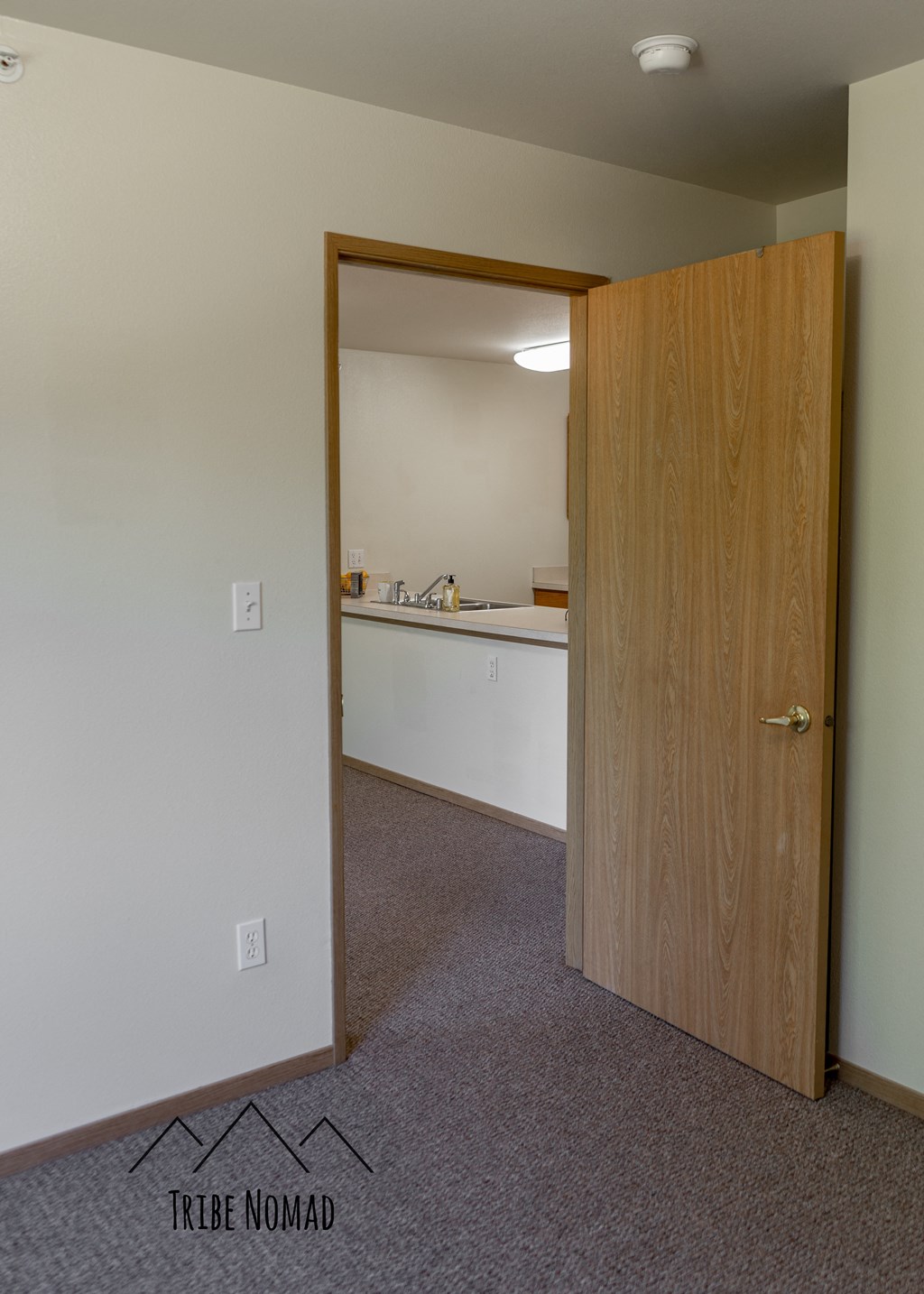 an empty room with a door to a kitchen