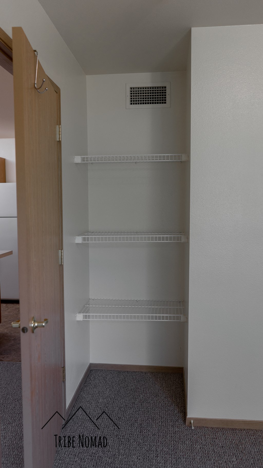 a door to an empty closet in a room with empty shelves