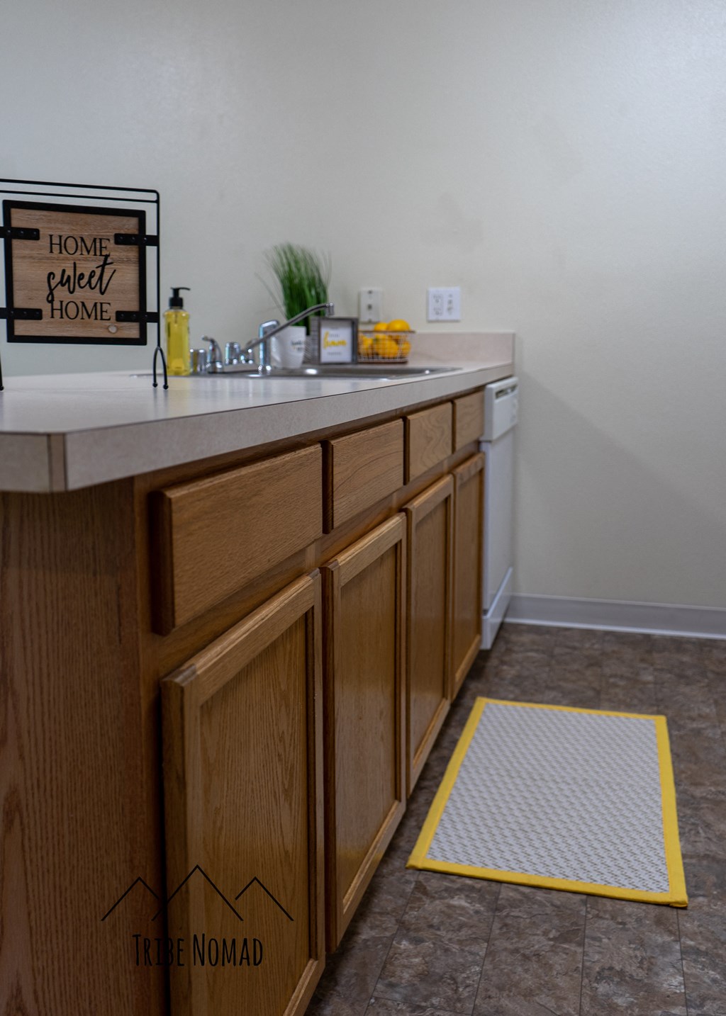 a kitchen with wooden cabinets and a sink and a yellow warning rug on the floor