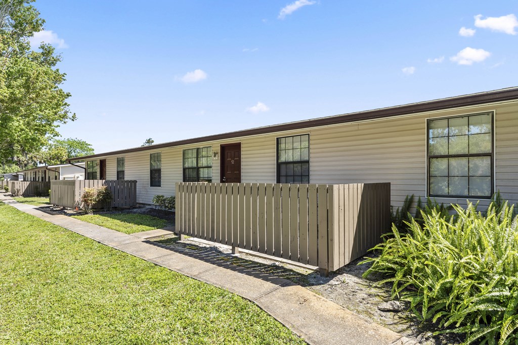 the exterior of a yellow house with a fence and grass