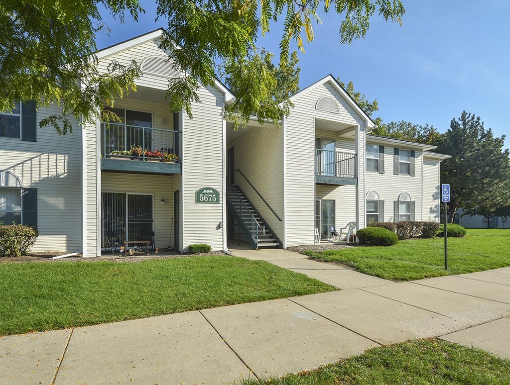 a white apartment building with a sidewalk in front of it