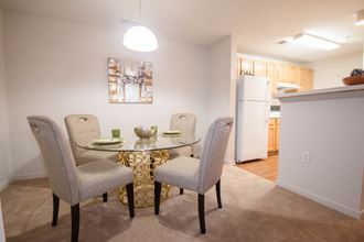 a dining room with a table and chairs and a kitchen with a refrigerator