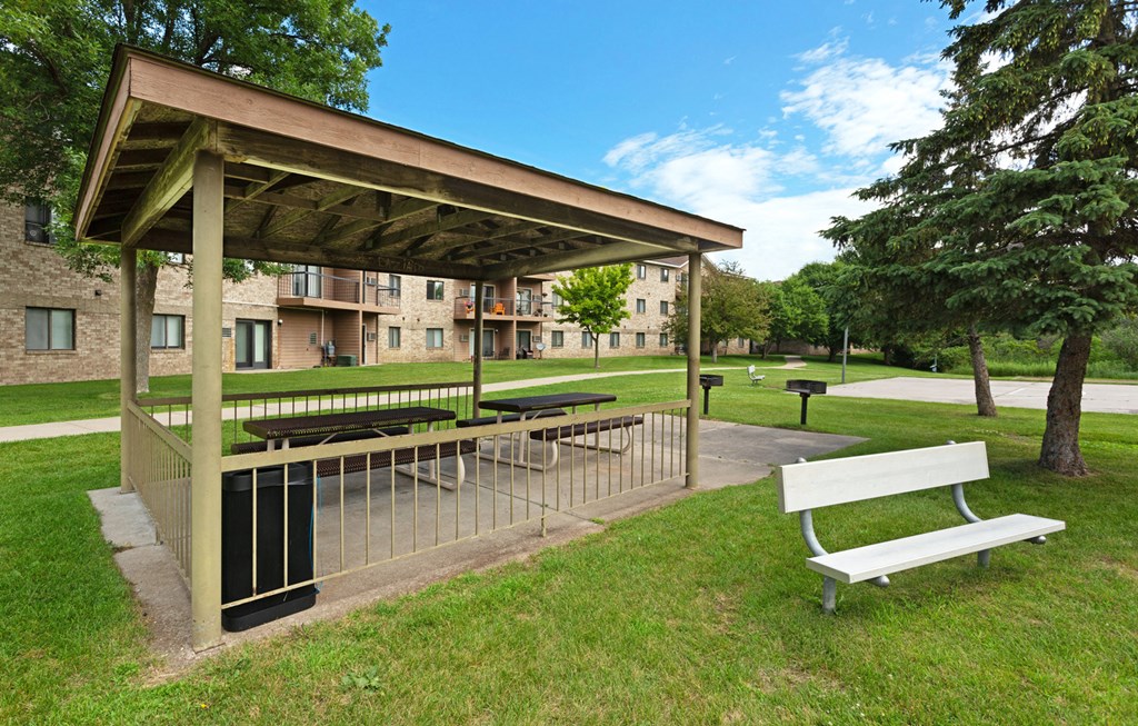a picnic table and a bench under a pavilion in a park
