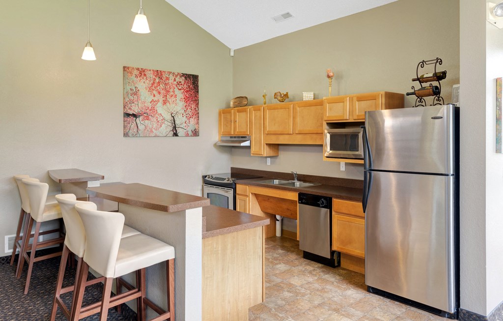 a kitchen with a stainless steel refrigerator and a counter with chairs