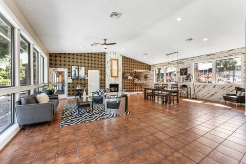A living room with a grey couch and a brown tiled floor.