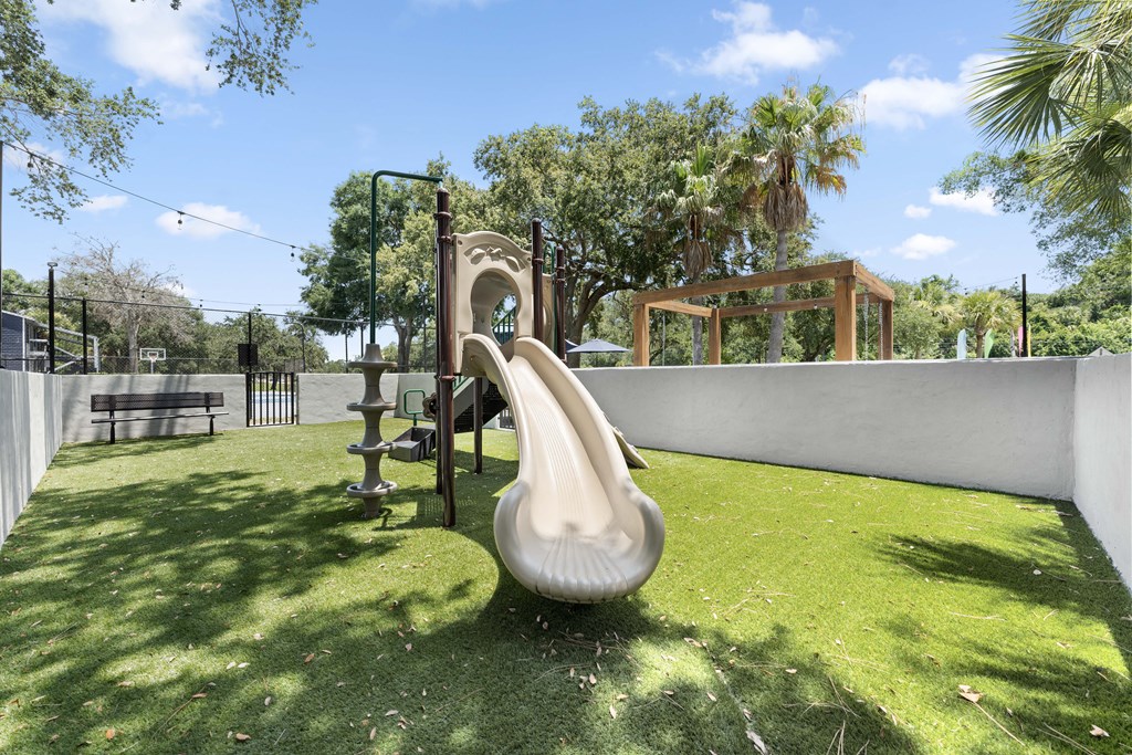 a playground with a slide and a swing set in a backyard