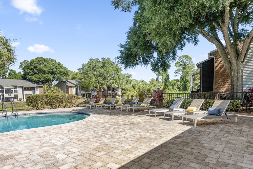 a swimming pool with chaise lounge chairs next to a house