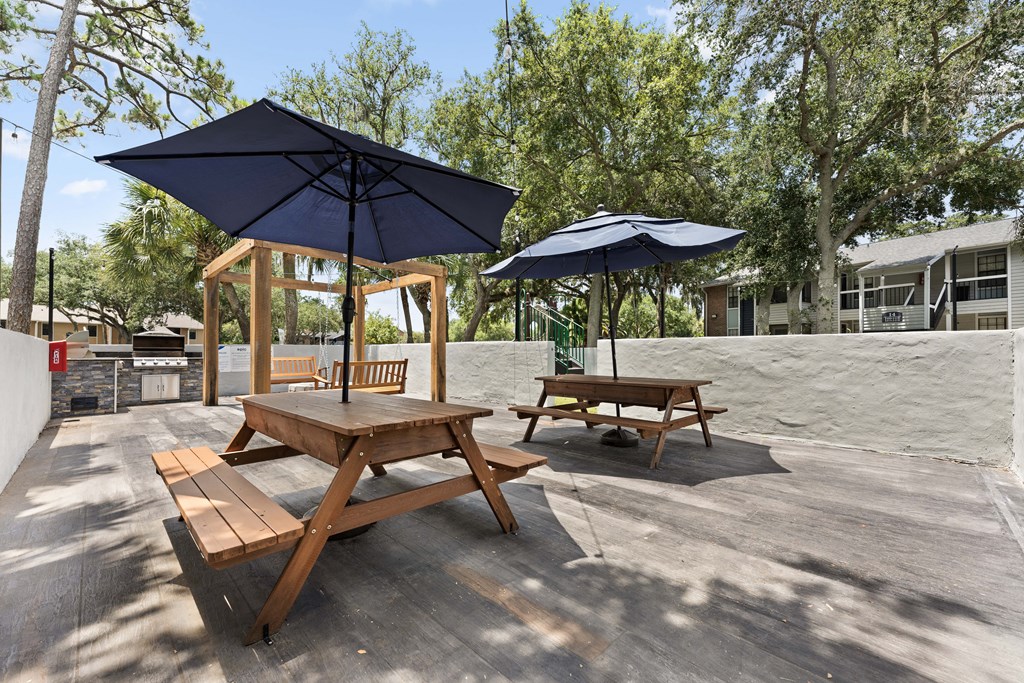 two picnic tables with umbrellas on a patio