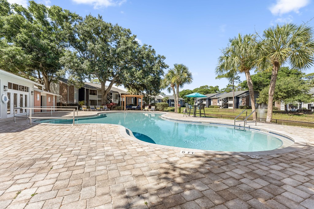 a resort style swimming pool with trees and buildings in the background