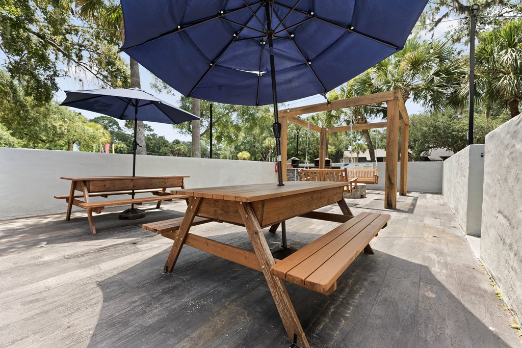 a picnic table with umbrellas and benches on a patio
