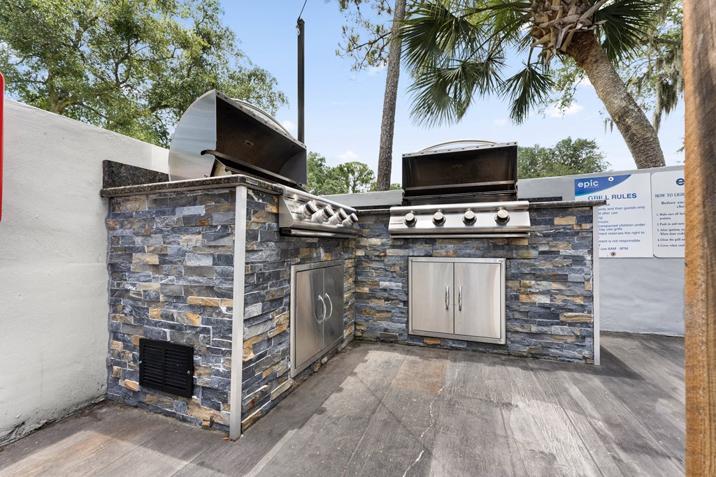 a barbecue grill with a stone wall and two stoves