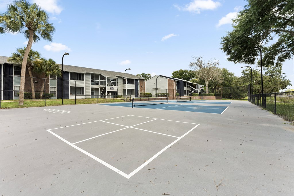 an empty basketball court with apartments in the background