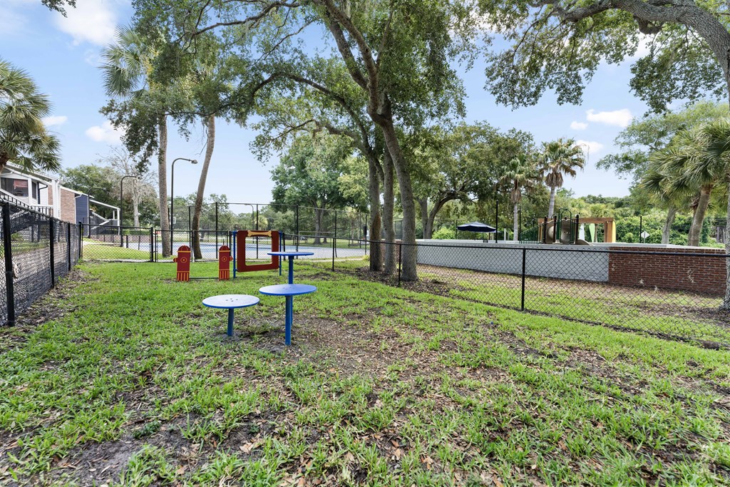 a playground and picnic table in a park with a tennis court