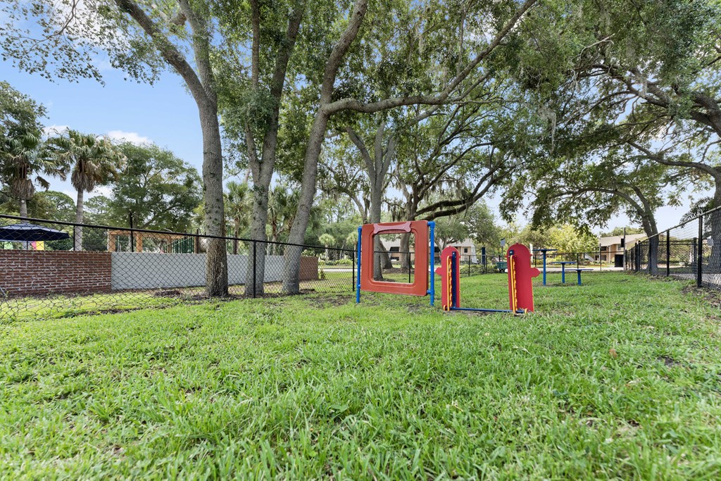 a park with a playground and a fence and trees
