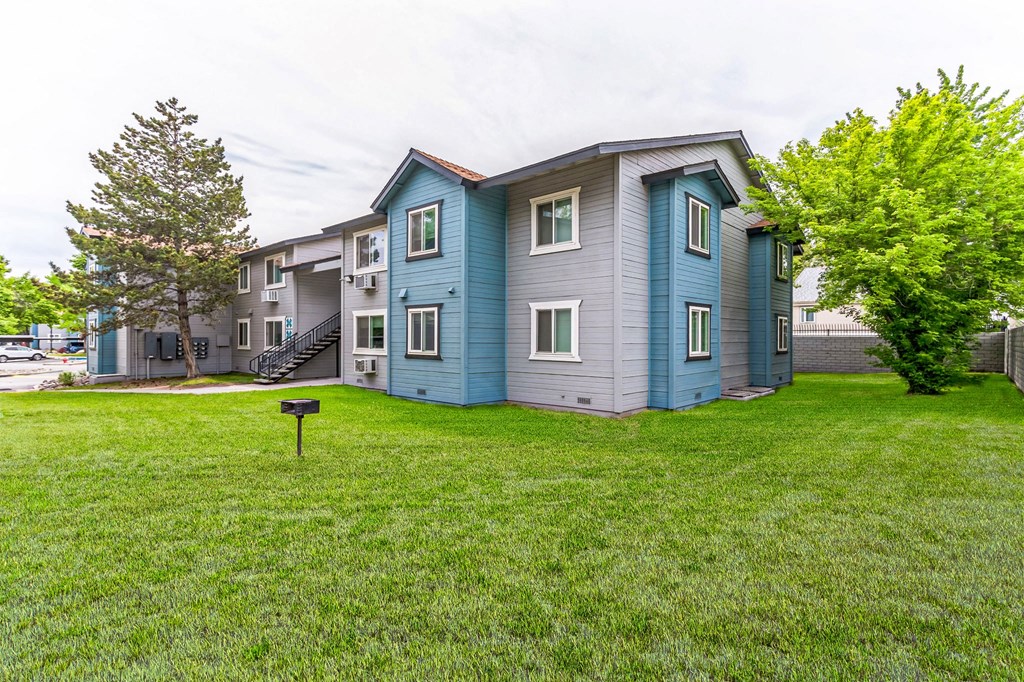 a blue and gray apartment building on a grassy lawn