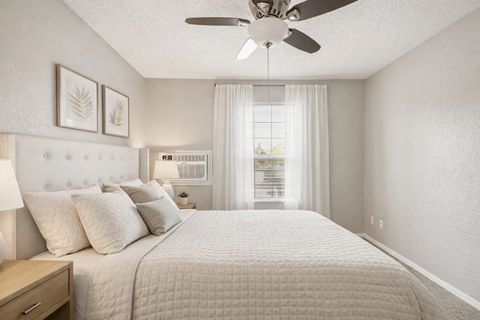 A bedroom with a large bed and a ceiling fan.