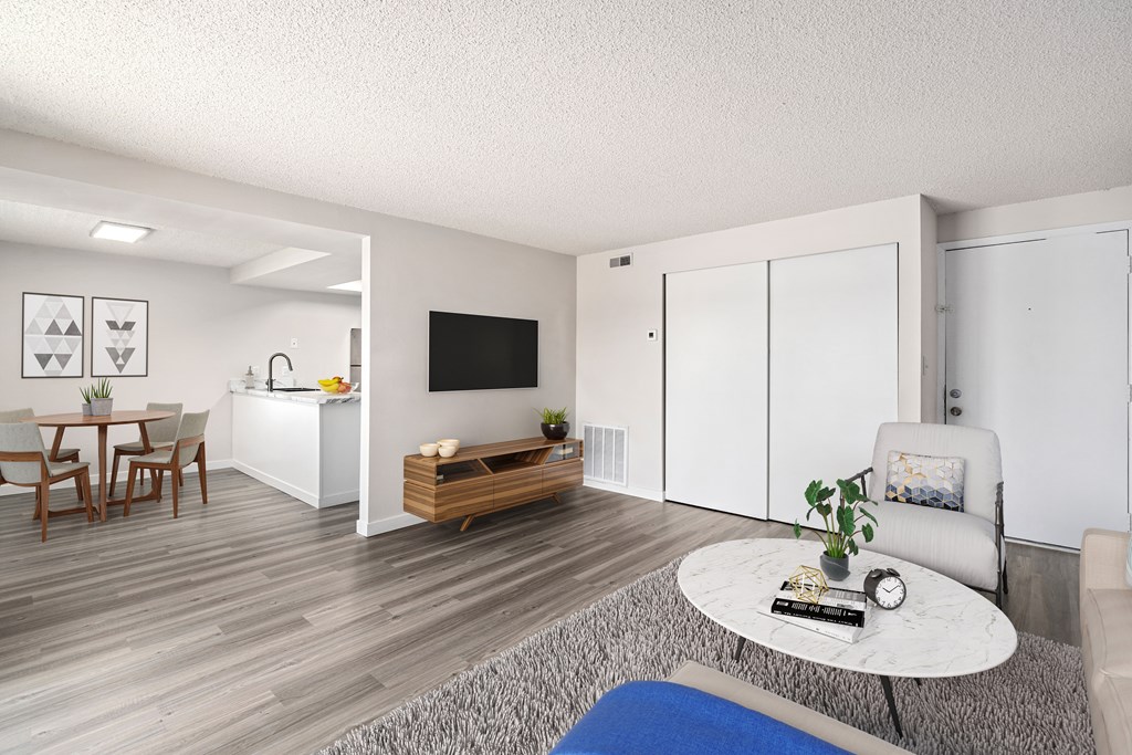 A living room with a white sofa, a grey coffee table, a wooden bench, and a dining table with chairs.