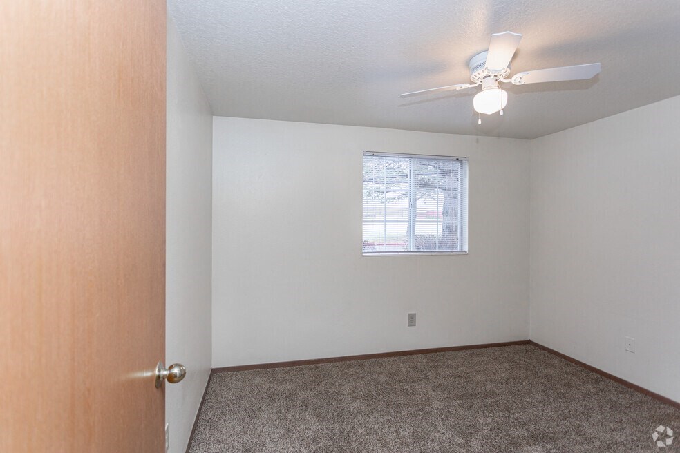 an empty living room with a ceiling fan and a window