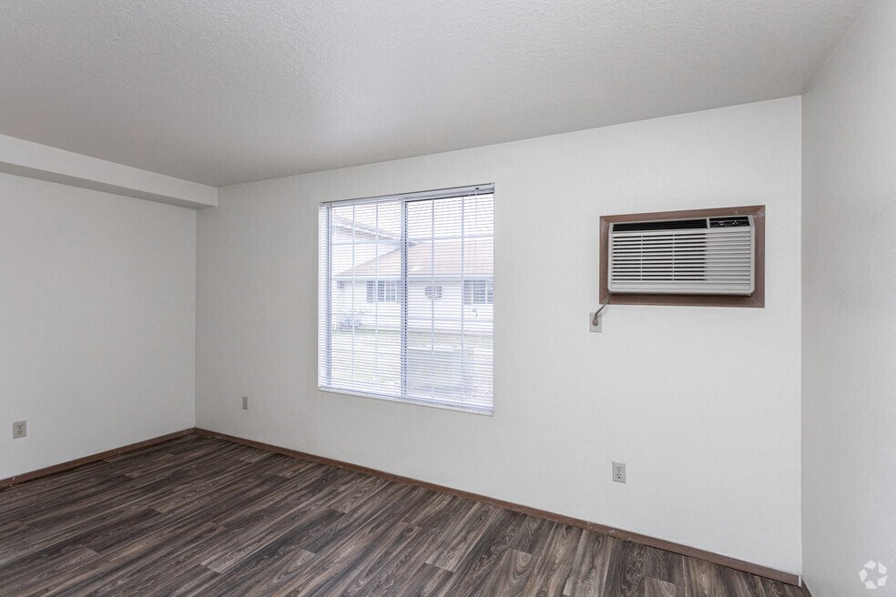 the living room of an apartment with a window and wood flooring