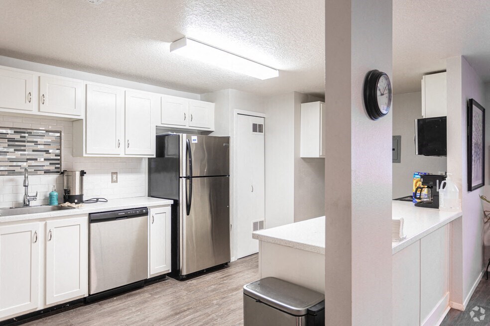 a kitchen with white cabinets and a stainless steel refrigerator