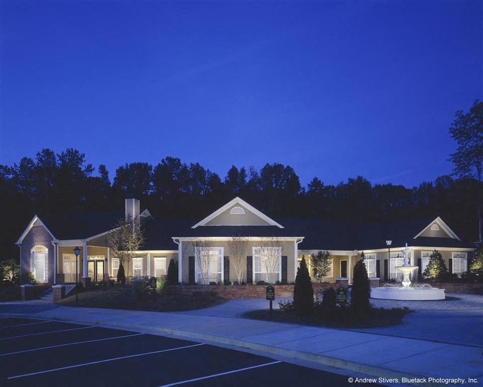 a house with lights on in a parking lot at night
