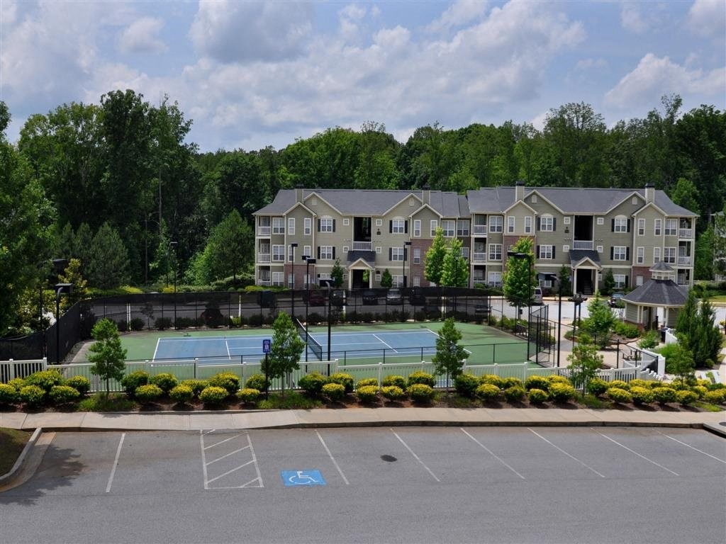 a tennis court in front of a building with apartments in the background