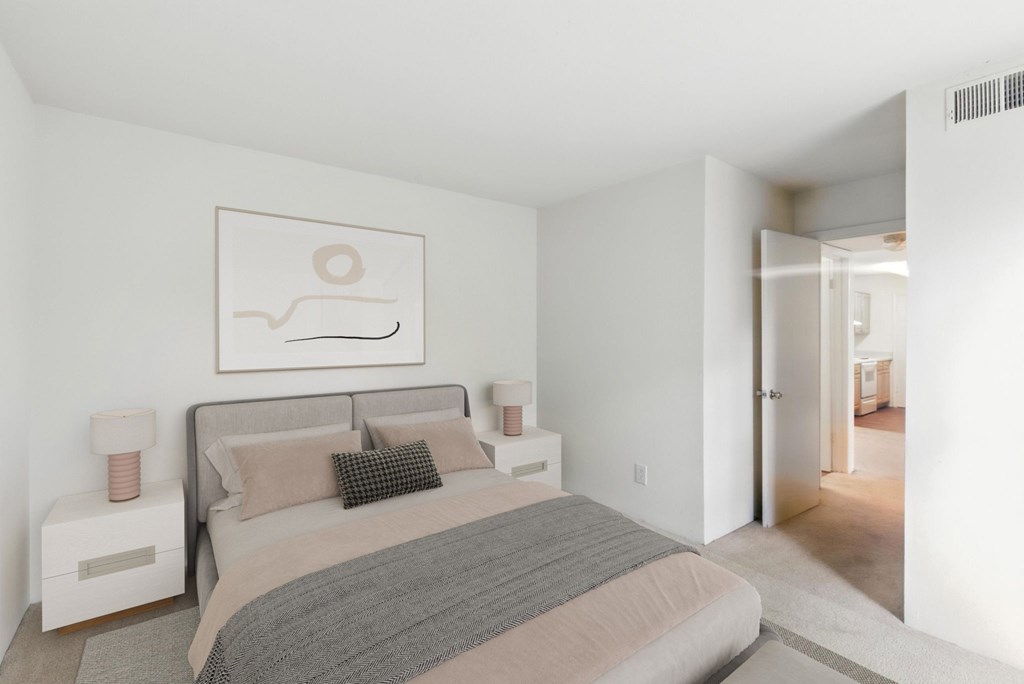 A bedroom with a bed, nightstands, and a painting on the wall.