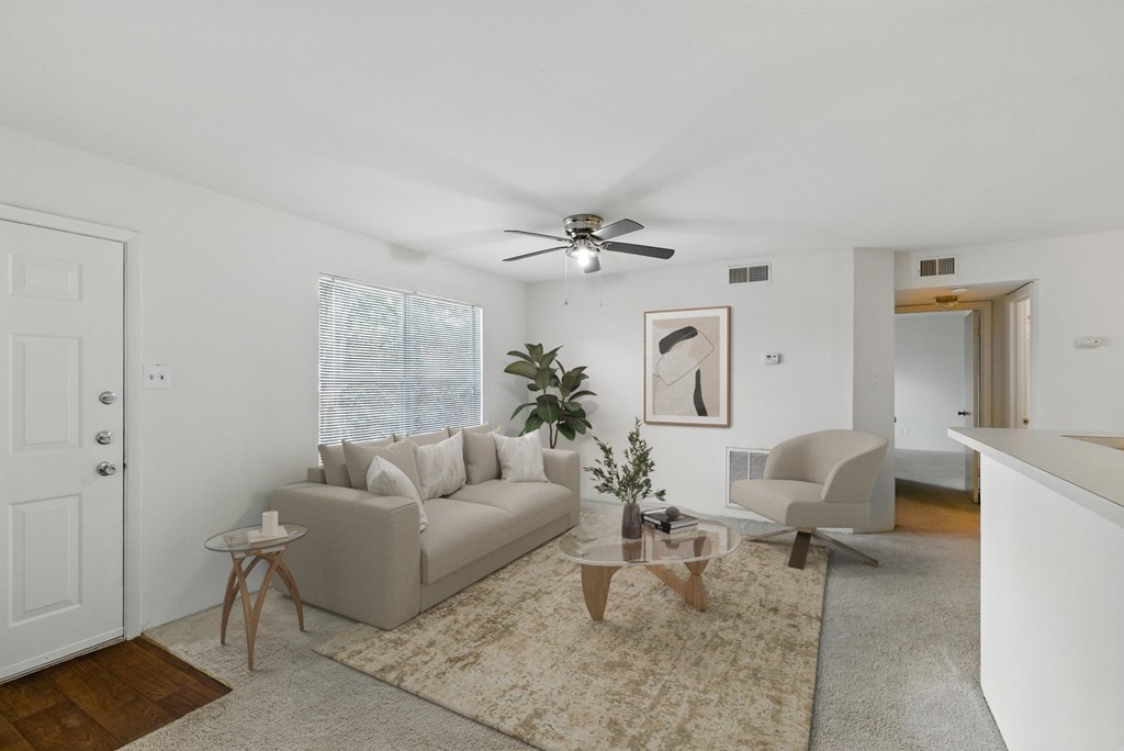A living room with a beige couch, a coffee table, and a ceiling fan.