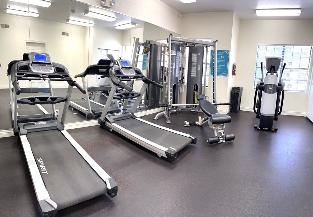 a gym with cardio equipment and weights on the floor