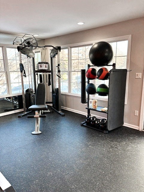 A home gym with a variety of equipment including a weight rack, a bench, and a large ball.