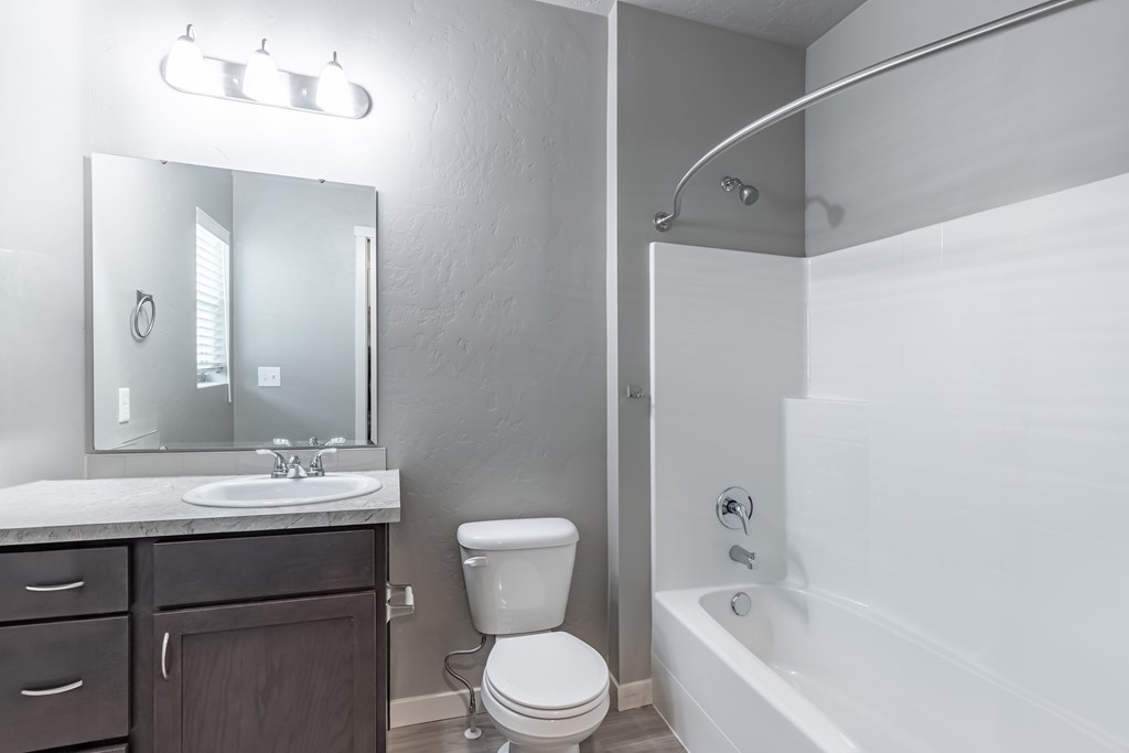 A white bathroom with a toilet, sink, and bathtub. at Harper Ridge Apartments, Meridian, ID, 83642